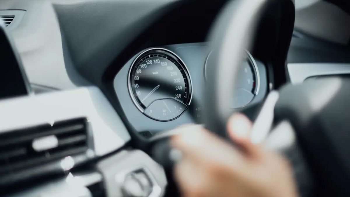 Lenkrad mit Tachometer in einem Sportwagen, Hand am Schaltknauf